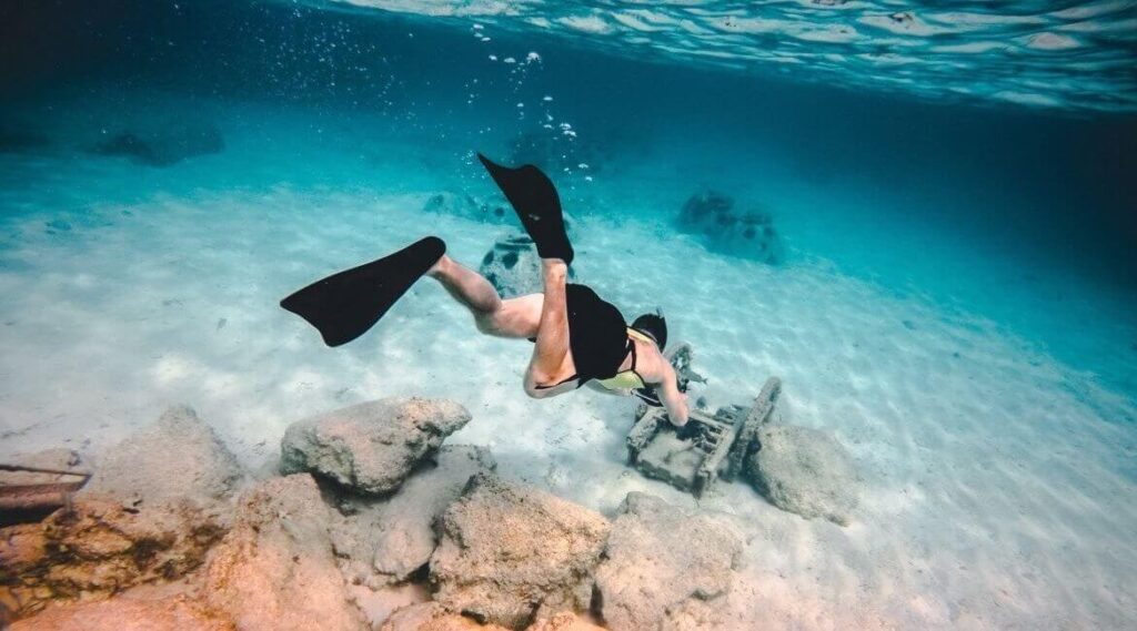Mann mit Schwimmflossen taucht zu Wrack